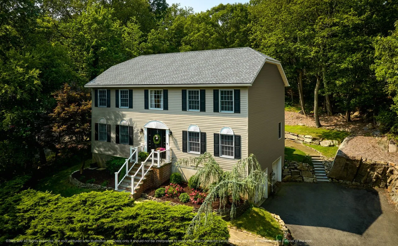 A two-story beige house with new shingles by National Roofing St. Louis after roof inspection and roof replacement from storm damage.