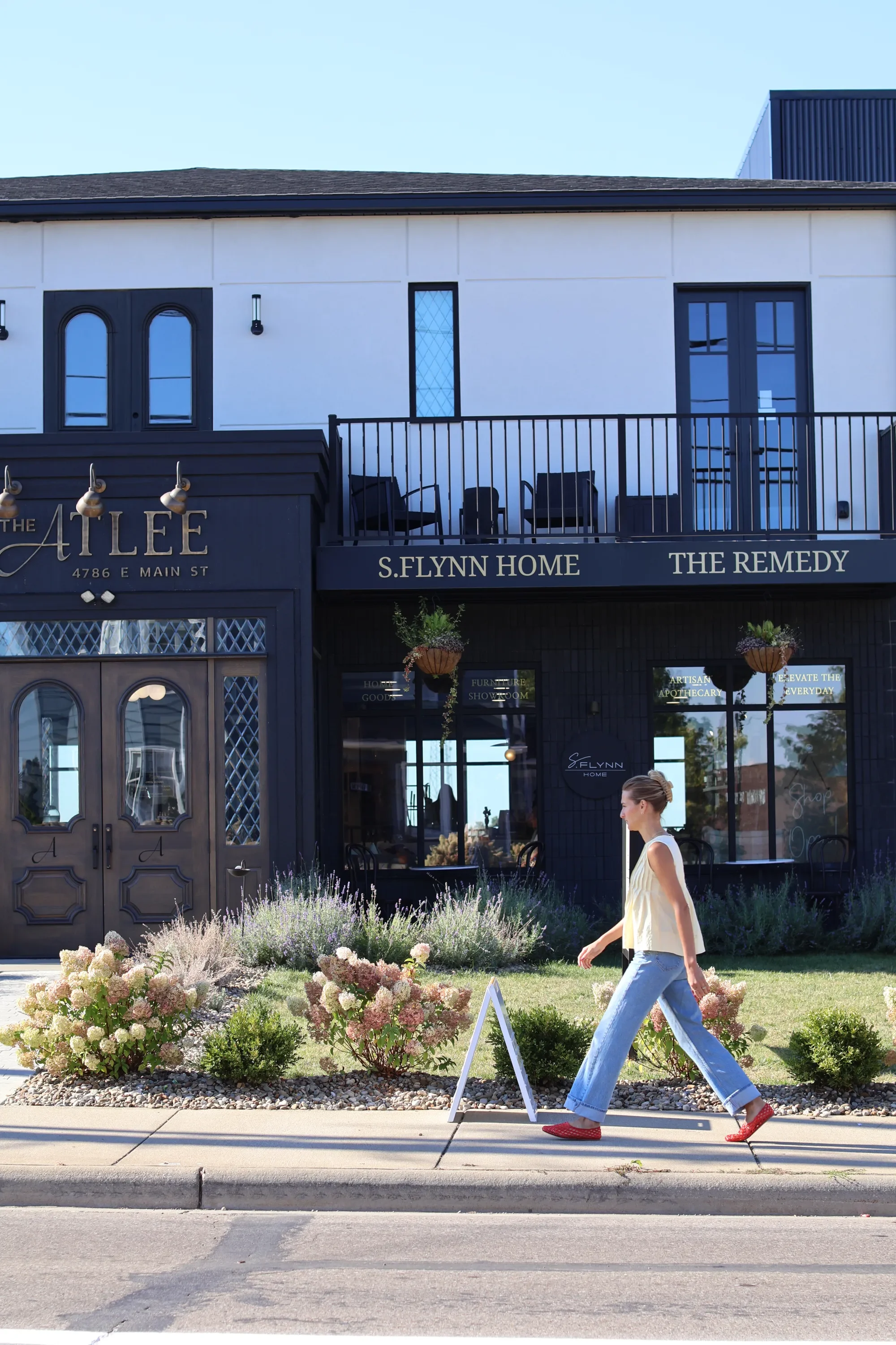 S Flynn Design + Build founder Sadie Beachy walking in front of Atlee S. Flynn Home storefront
