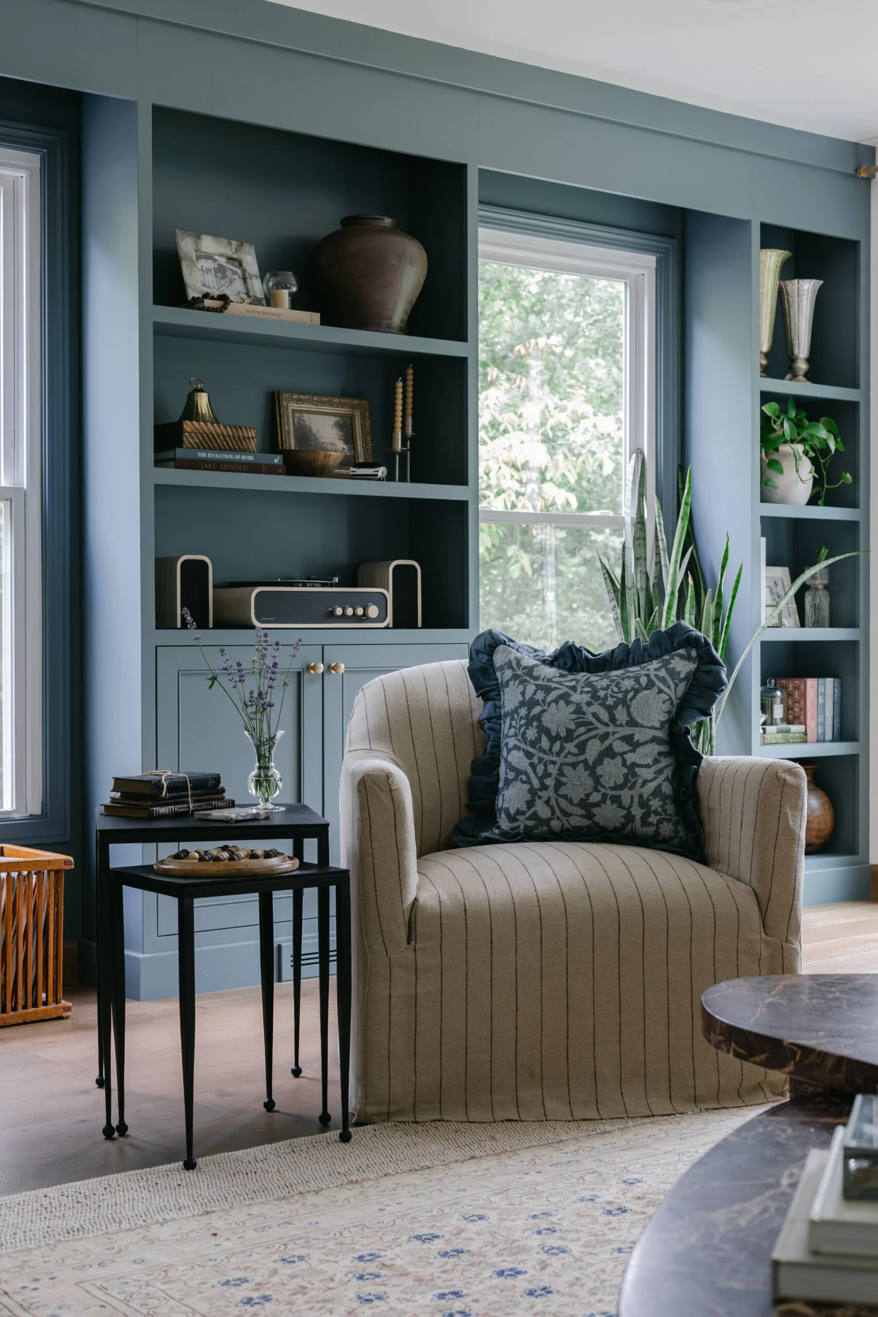 Blue built in shelving with beige striped arm chair in living room remodel and styling by S. Flynn Design + Build