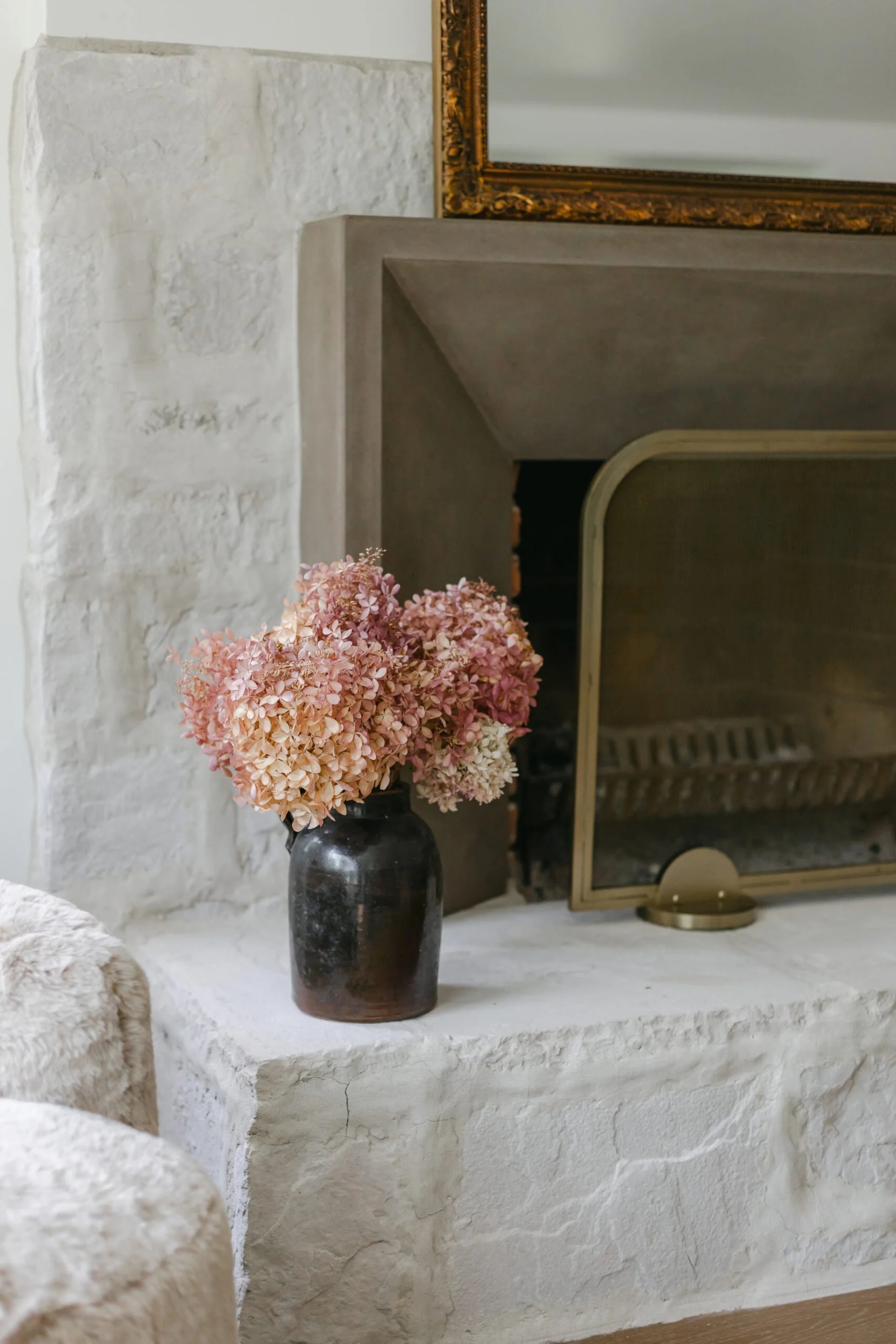White textured fireplace with golden fire place cover in living room remodel by S. Flynn Design + Build