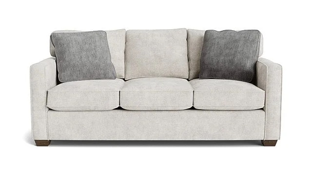 Light beige sofa with three cushions, two dark gray and one lighter gray, on a plain white background.