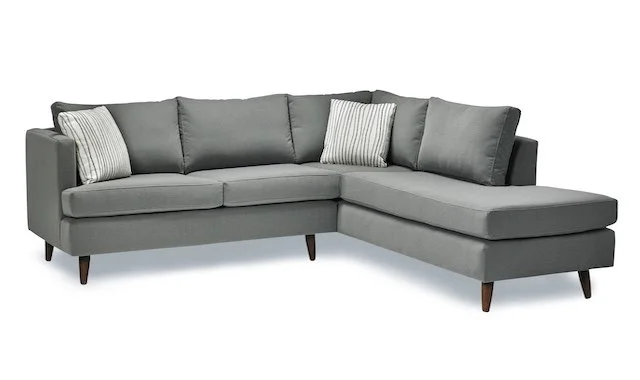 Gray sectional sofa with two striped throw pillows.