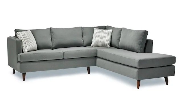 Gray L-shaped sectional sofa with two striped pillows.