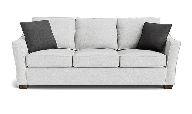 A light gray sofa with three cushions and two black throw pillows, wooden legs, against a plain white background.