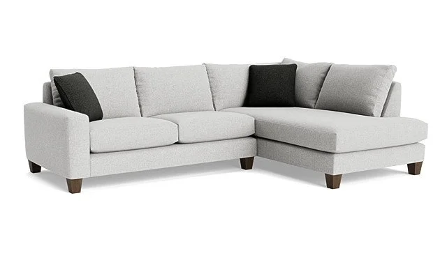 Light gray sectional sofa with three black pillows.