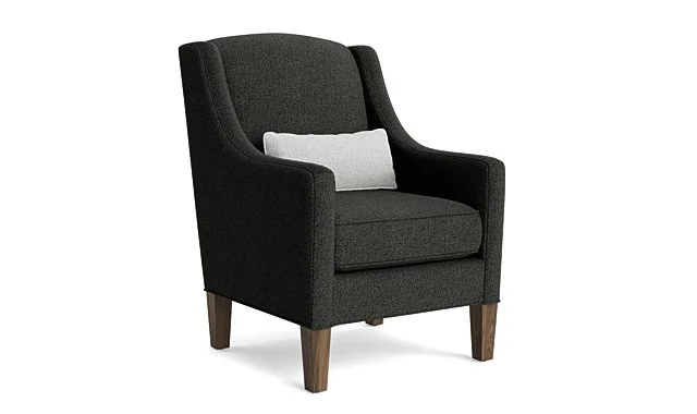A black upholstered armchair with wooden legs and a small gray pillow.