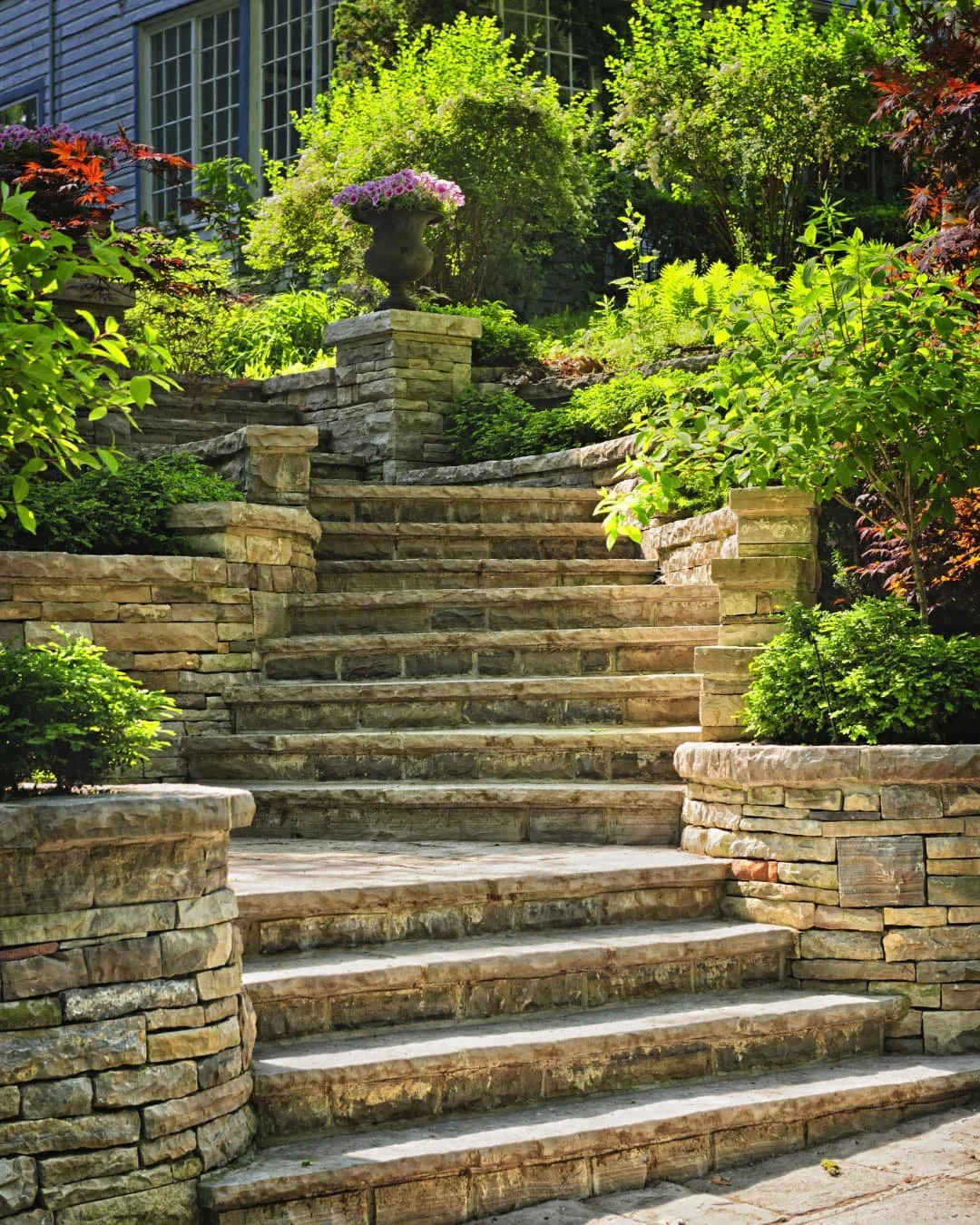 Curved stair inspiration with stone steps and retaining walls leading into a landscaped outdoor space.
