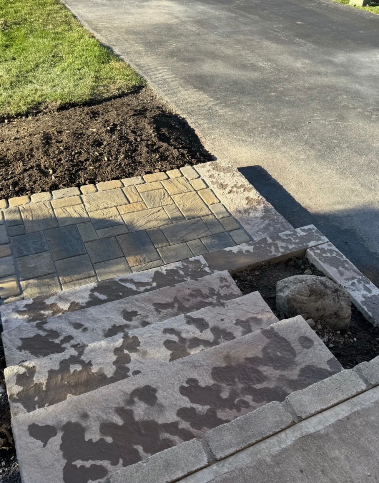 Front entry steps and landing at a Fayetteville, NY home with updated stonework and a polished hardscape finish.