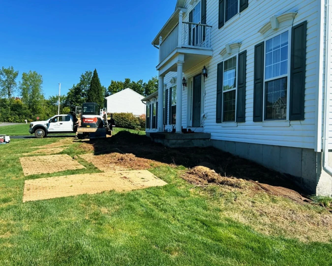 Rear lawn view of a Skaneateles, NY home showing a completed hardscape and landscaping project.