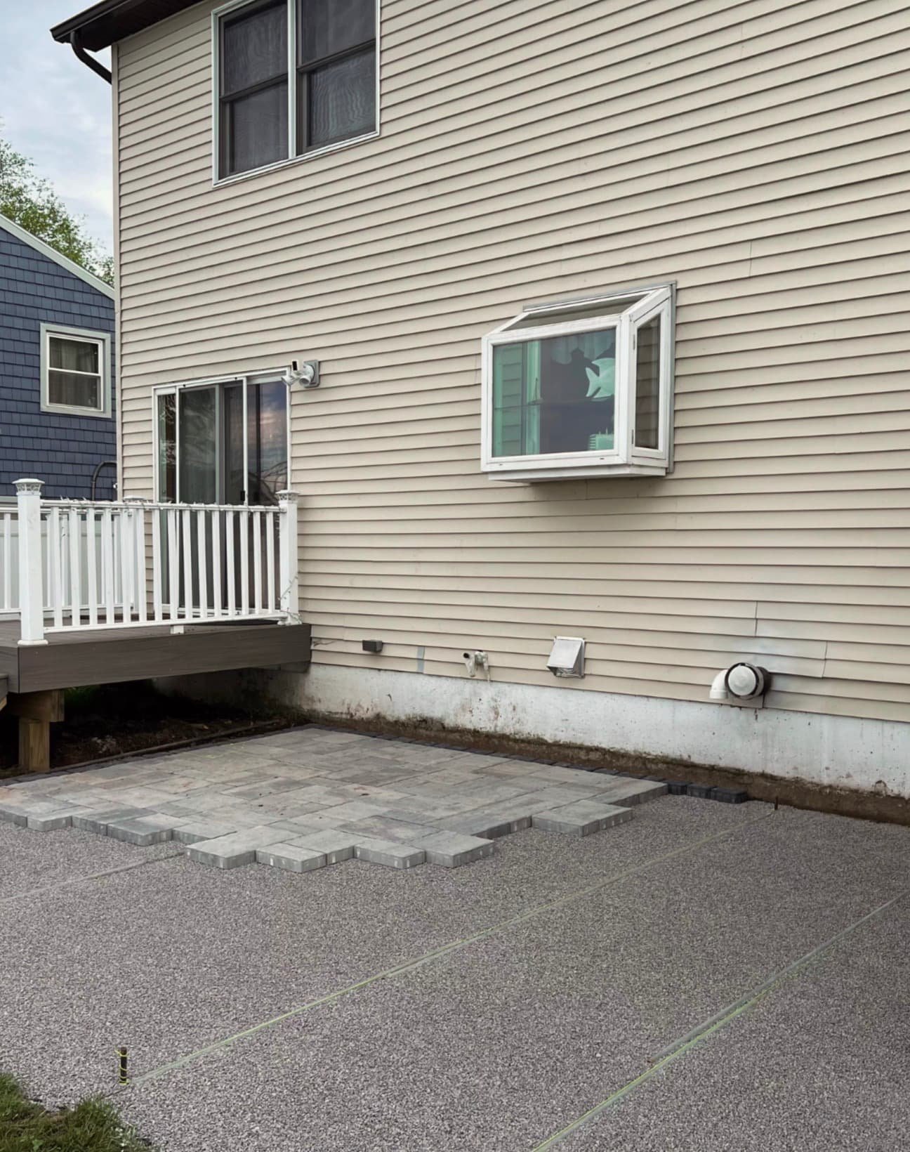 Rear patio installation at an Upstate New York home showing completed paver work beside the house.