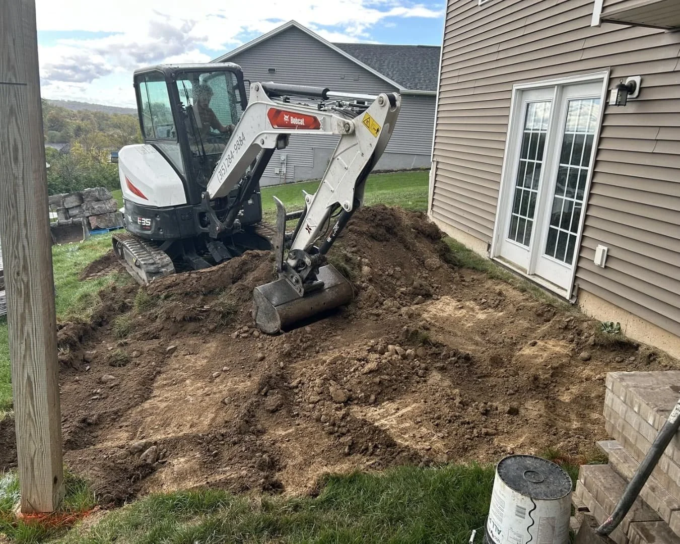 Side yard view of a home with completed grading and hardscape improvements in Central New York.