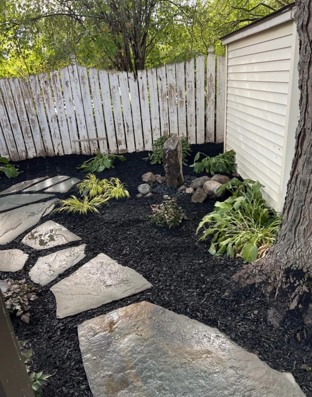 Mulch bed and stepping stone path at a Central New York home with neat edging and updated backyard landscaping.