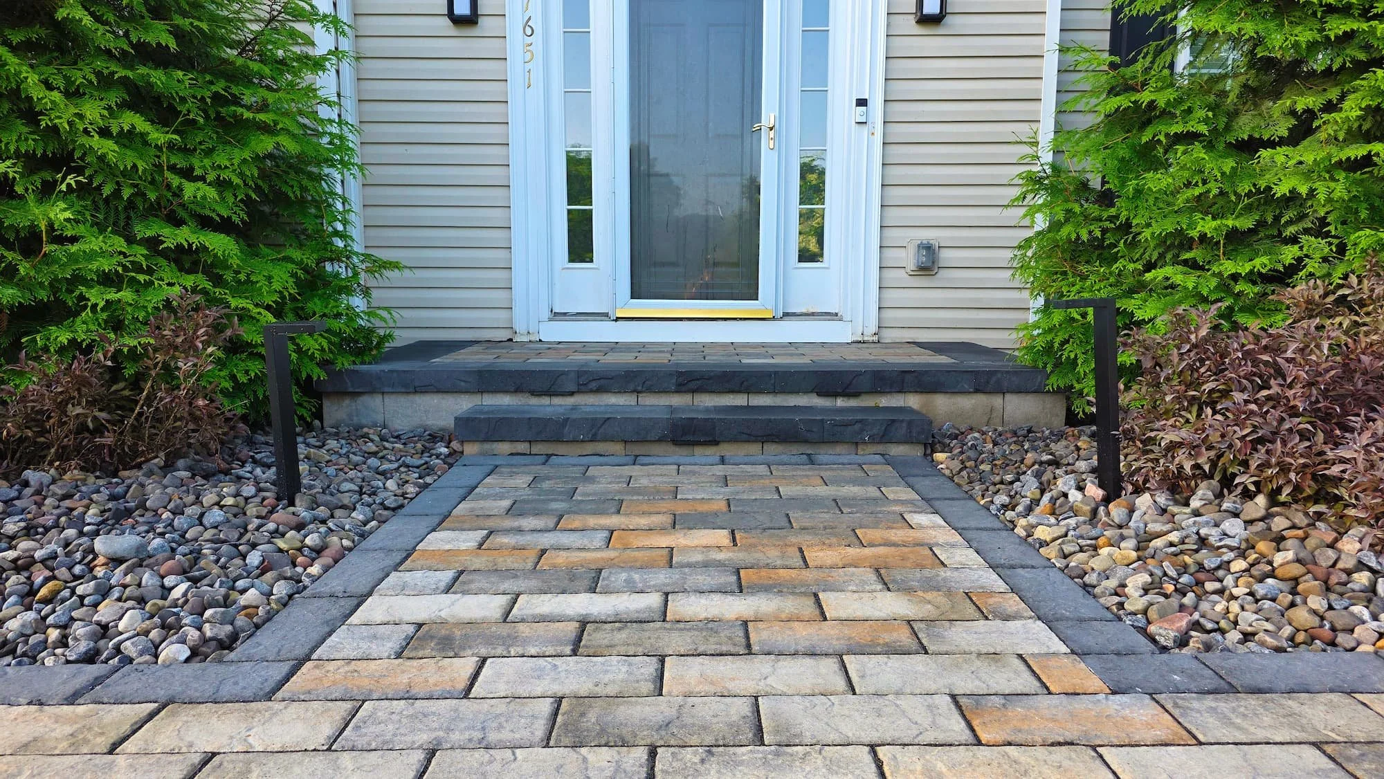 Residential landscape design with shrubs, stone accents, and lawn surrounding a Central NY home.