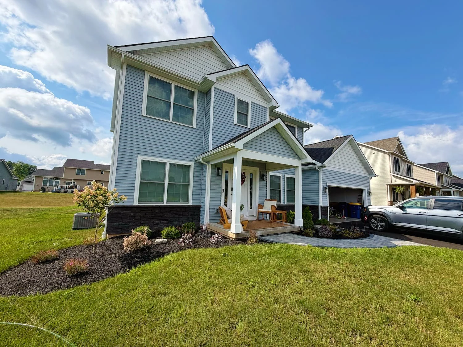 Foundation landscaping with shrubs, ornamental plants, and a mulched garden bed in Central NY.