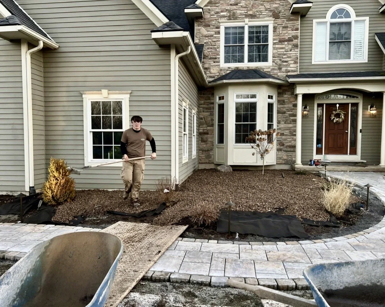 Front planting bed preparation at an Upstate New York home with paver edging and newly shaped soil.