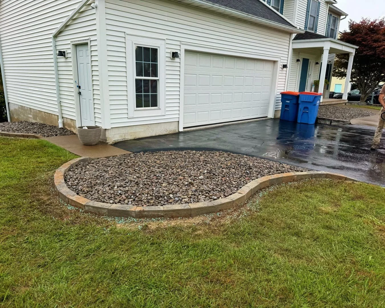 Round stone island bed by the driveway completed by Pines and Pavers in Lysander, New York.