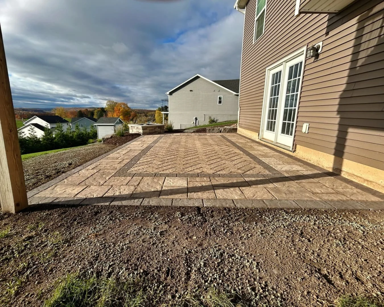 Under-deck patio and backyard overview completed by Pines and Pavers in Lysander, New York.