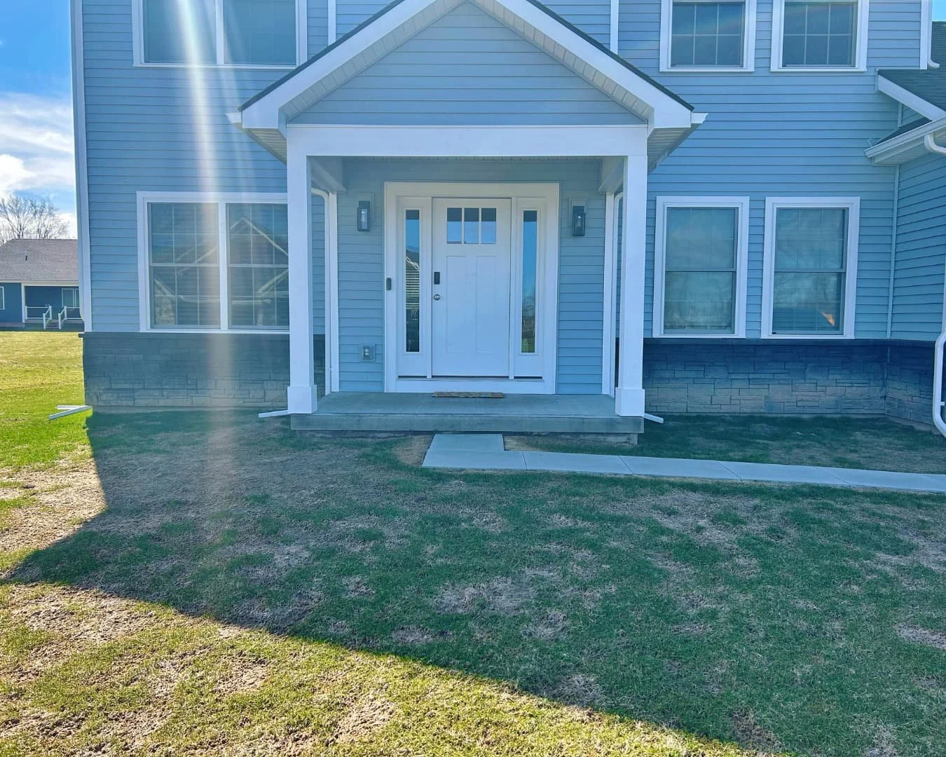     Front yard of a residential home before walkway installation, showing the entry area and open lawn.