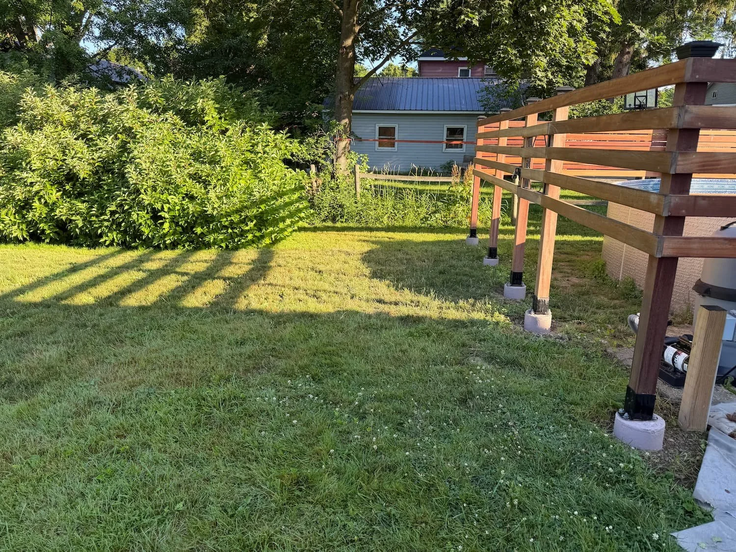 Ground preparation underway beside a wood deck for a residential paver project in Central New York.
