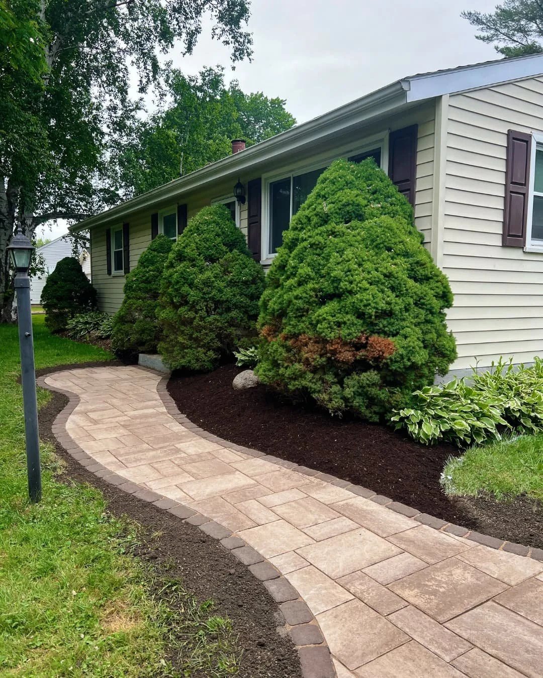 Curved paver walkway and foundation bed completed by Pines and Pavers in Central New York.