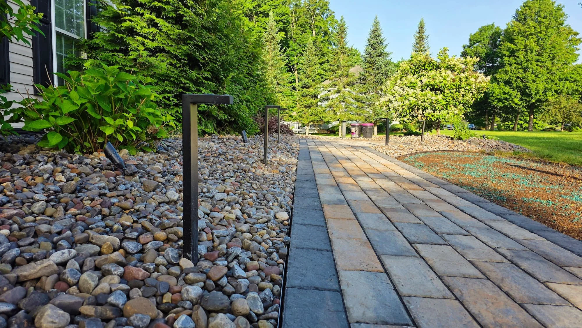 Curved paver walkway surrounded by decorative stone and established landscaping in Central NY.