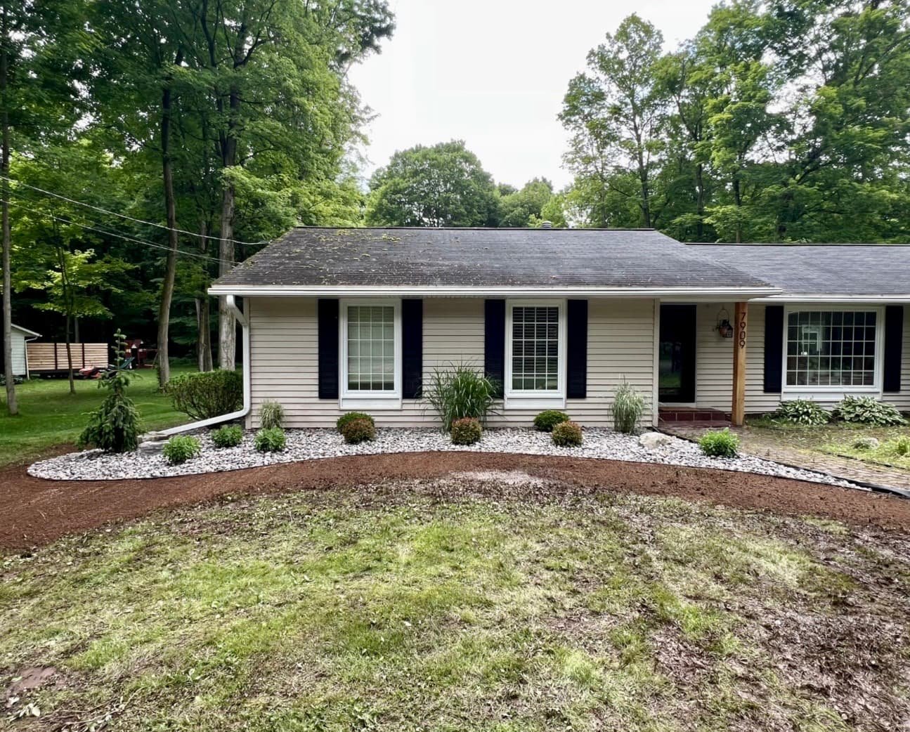 Curved stone border landscaping at a Central New York home with mulch beds, shrubs, and a polished front entry look.