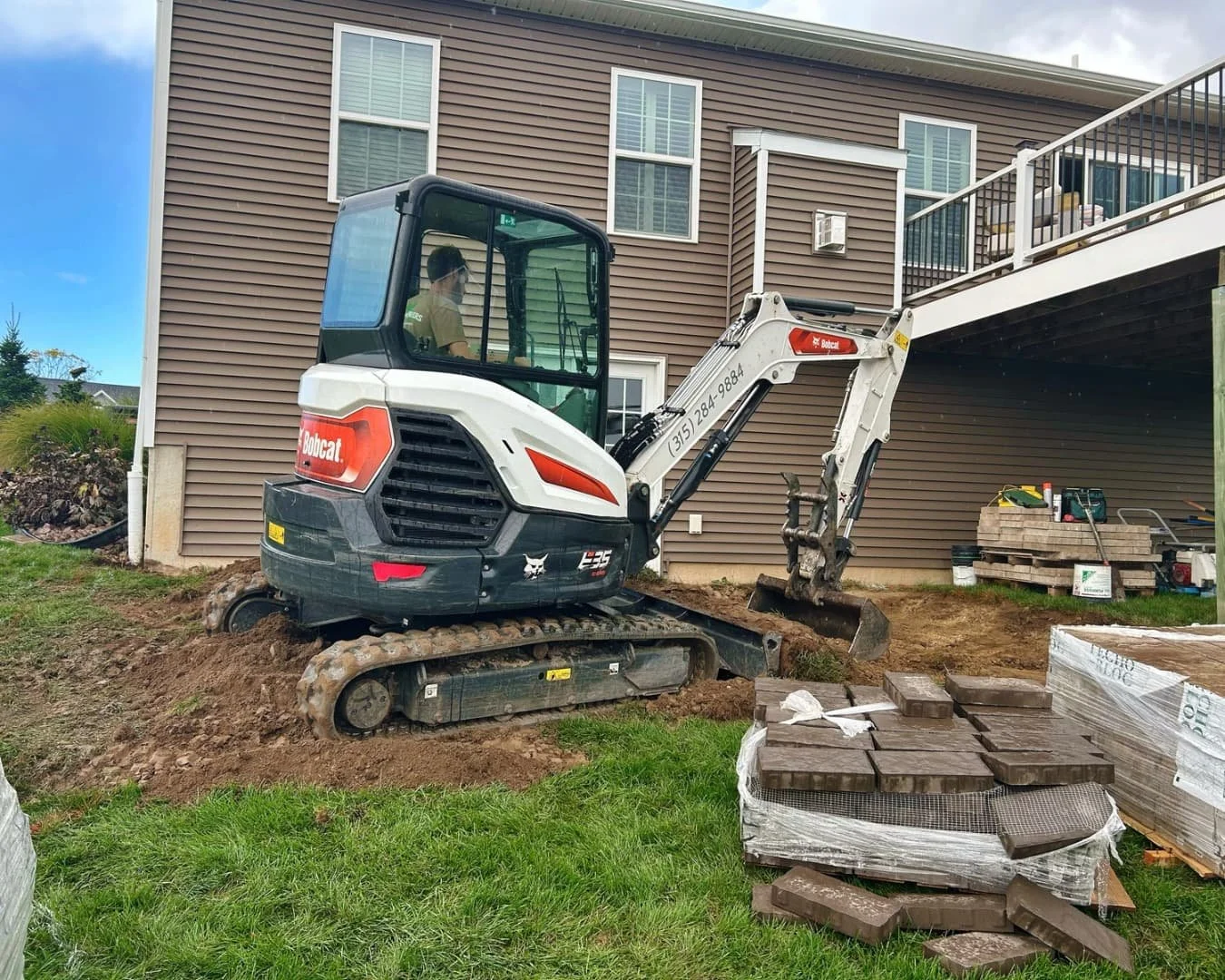 Excavation beside the home before patio installation by Pines and Pavers in Lysander, New York.