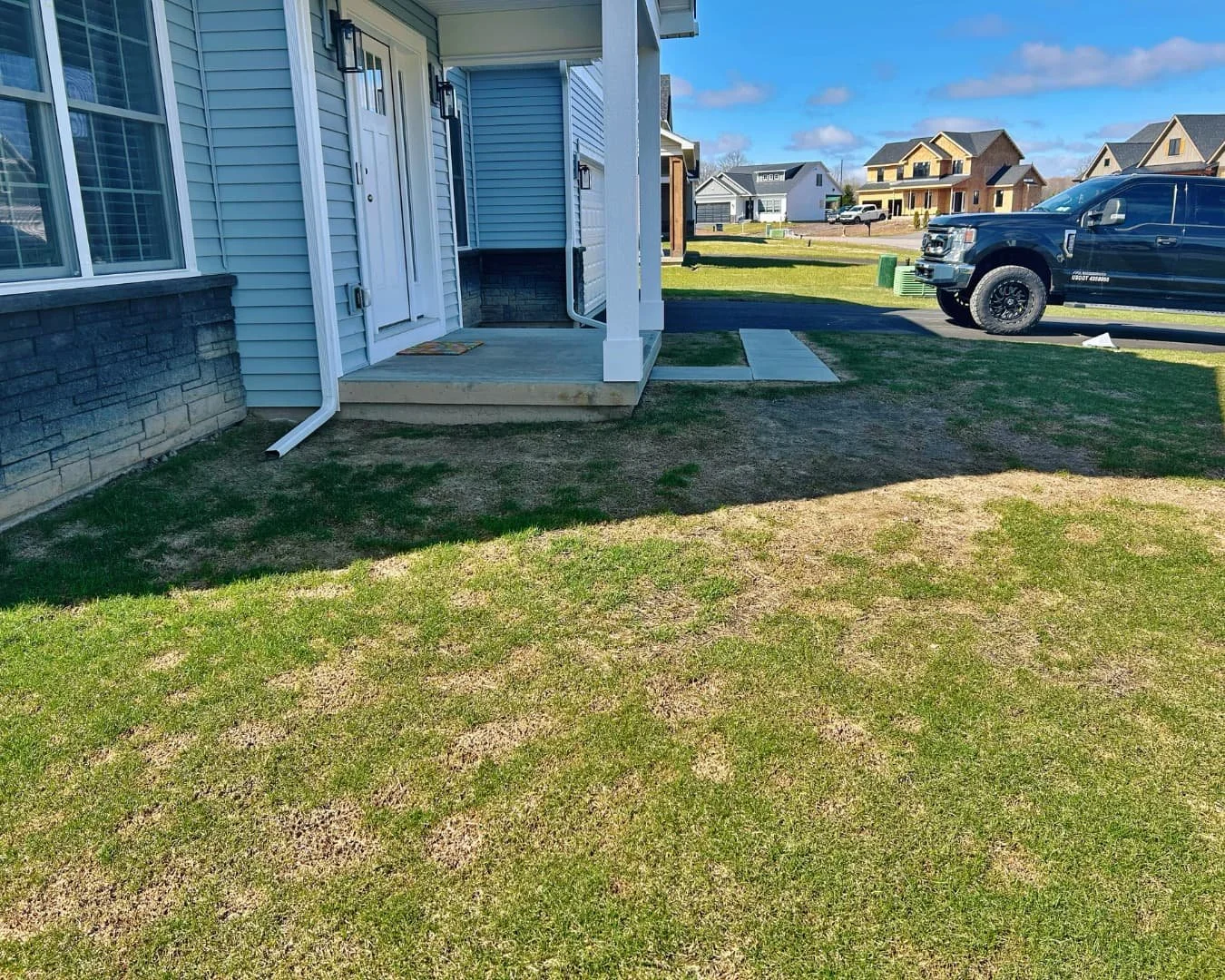     Residential home exterior before front walkway project, showing lawn and unfinished entry access.