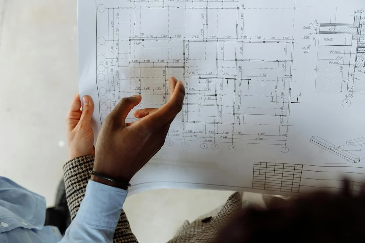 Person reviewing architectural blueprints and construction plans during a residential design and planning meeting.