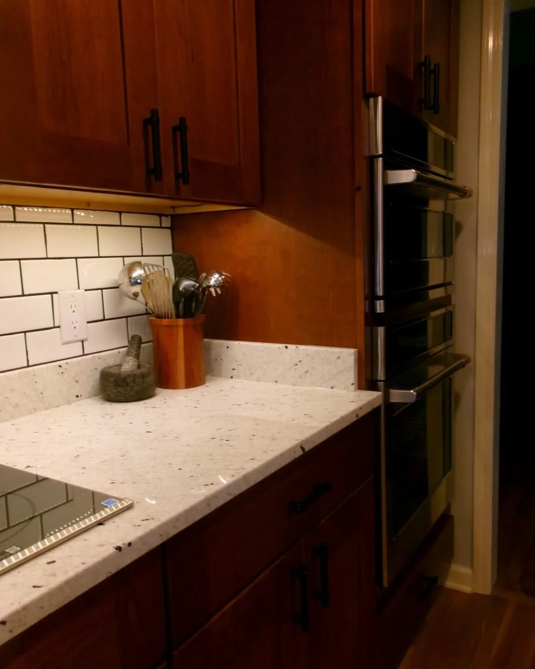 Kitchen counter and backsplash in an Upstate New York renovation with granite surfaces and warm wood cabinets.