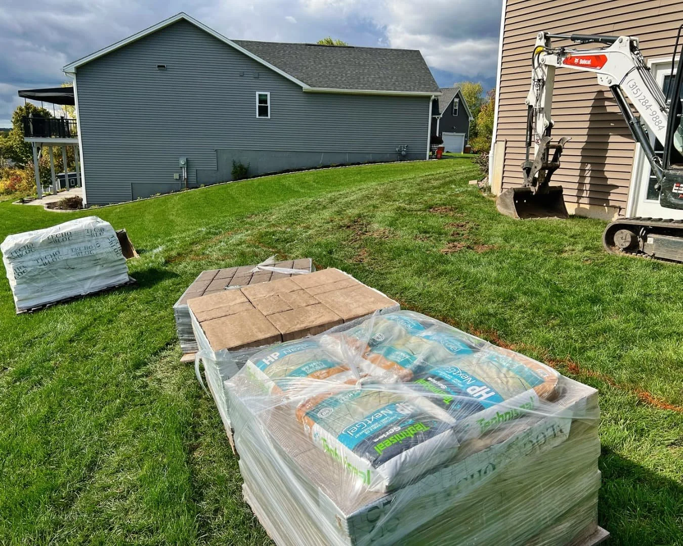 Paver materials and equipment on site for a Pines and Pavers project in Lysander, New York.