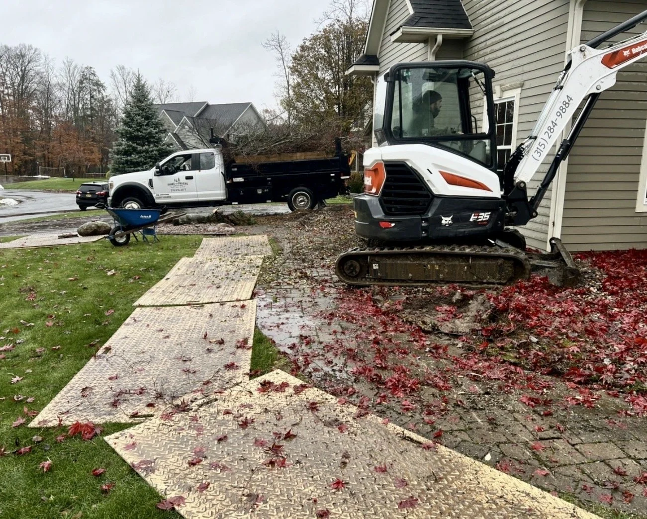 Landscape installation in progress at an Upstate New York home with equipment, fresh mulch, and active site work.