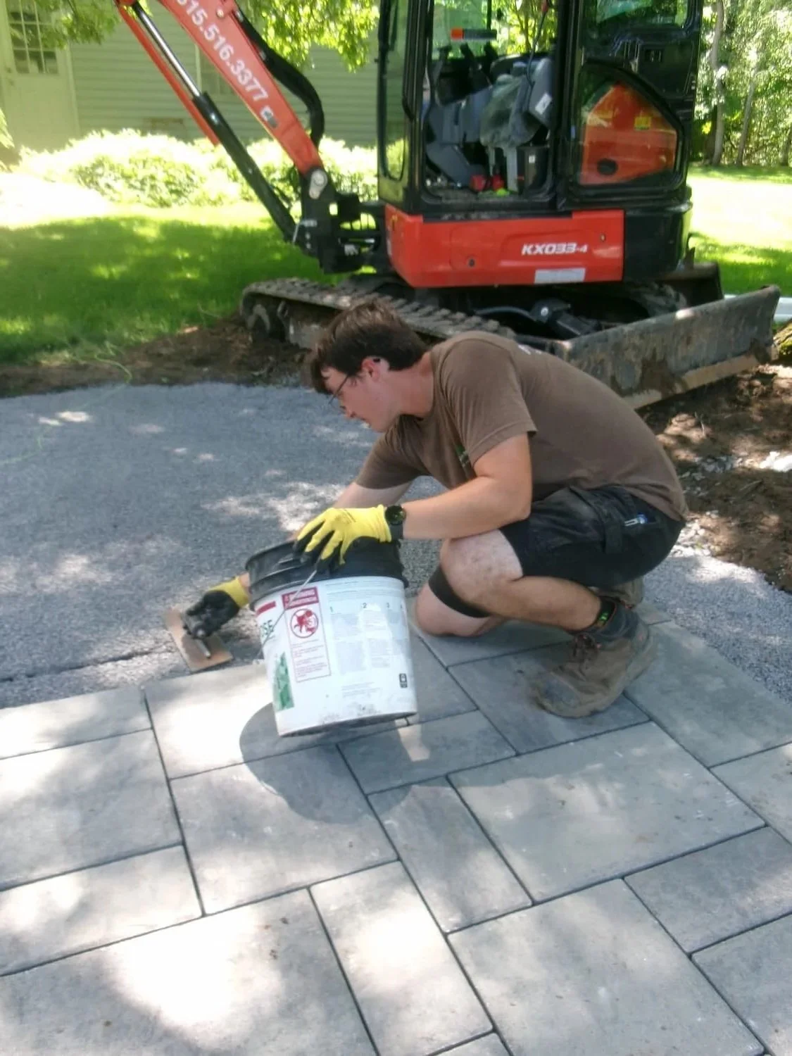 Hardscape professional installing custom pavers for a residential patio project near Syracuse, New York.
