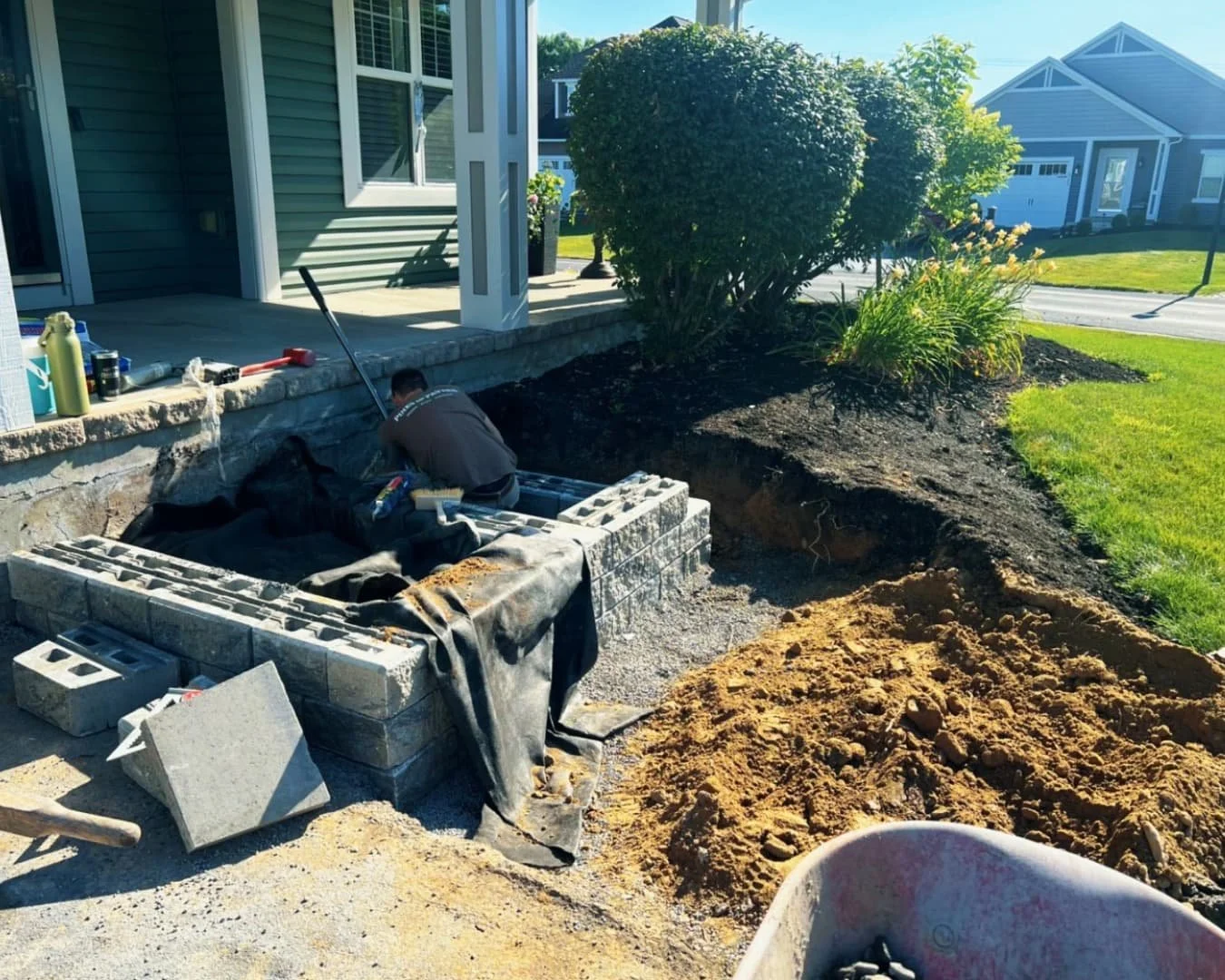 Front step construction detail at an Upstate New York home showing stone blocks, excavation, and active hardscape work.