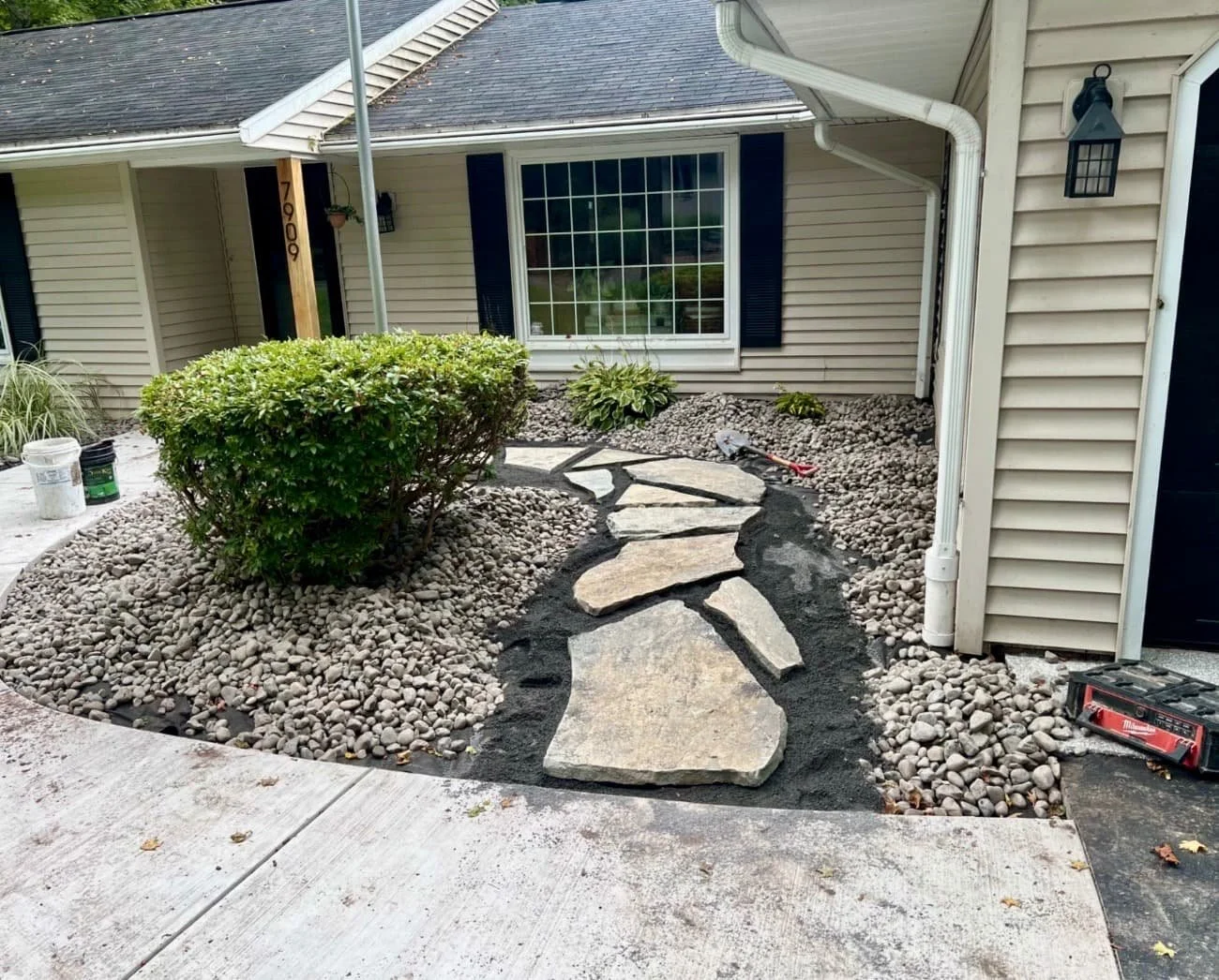 Front yard landscape bed at an Upstate New York home with curved mulch borders, decorative stone, and updated curb appeal.