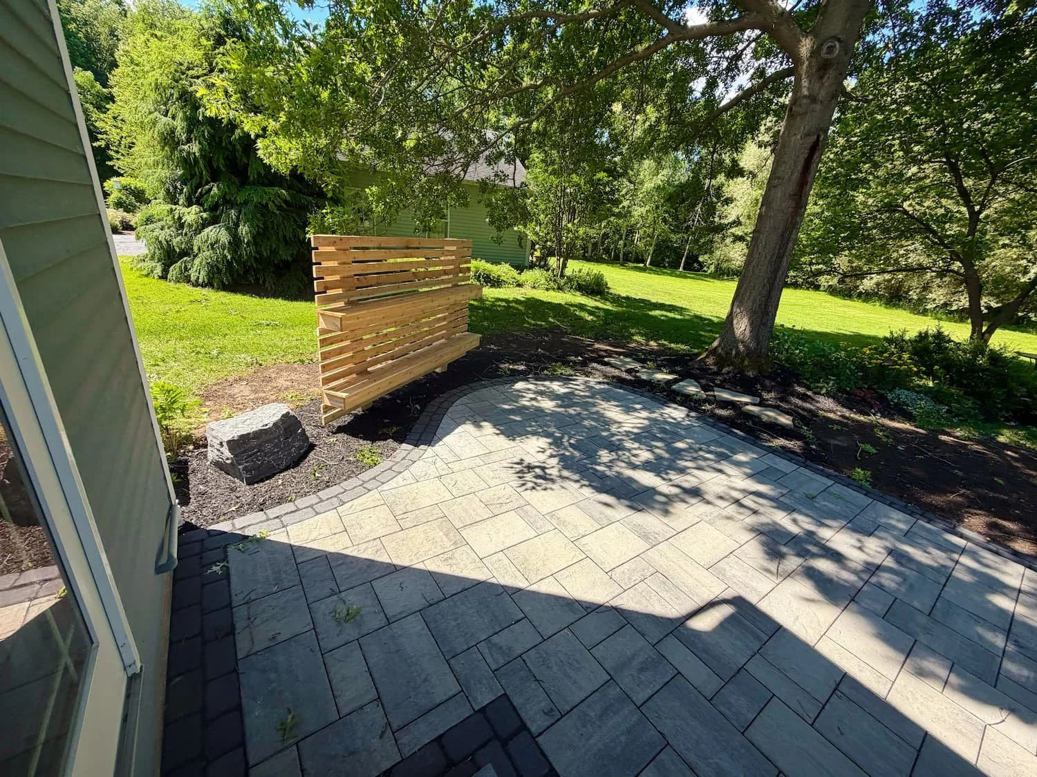 Backyard paver patio with built-in seating area professionally installed by Pines and Pavers in Central New York.