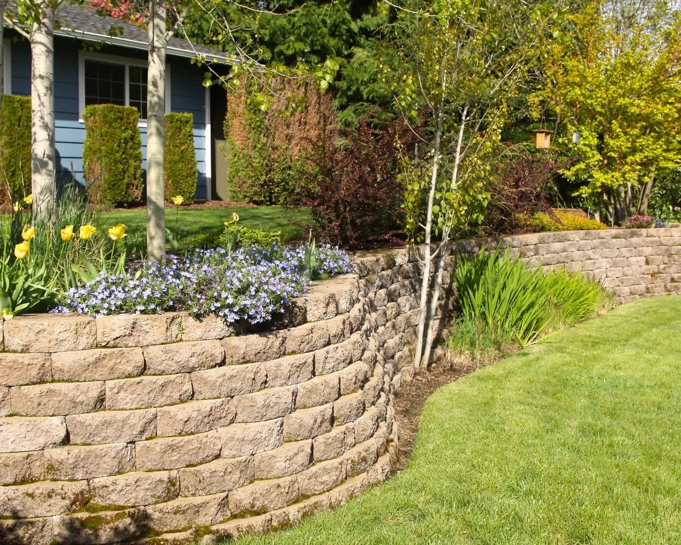 Retaining wall inspiration with stacked stone blocks creating a clean yard edge and grade separation.