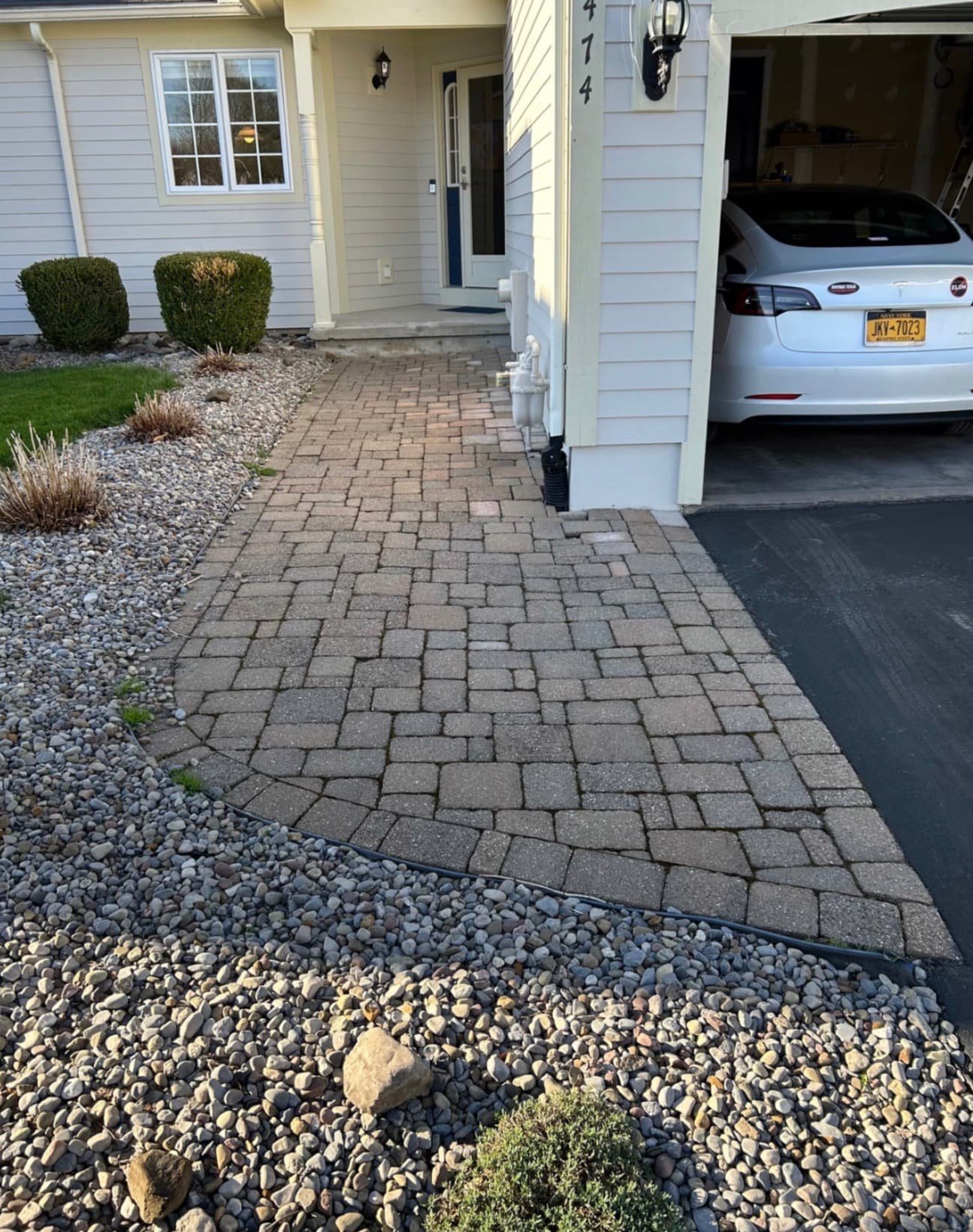 Front drive entry with paver hardscape at a Central New York home, connecting the driveway and front entrance.