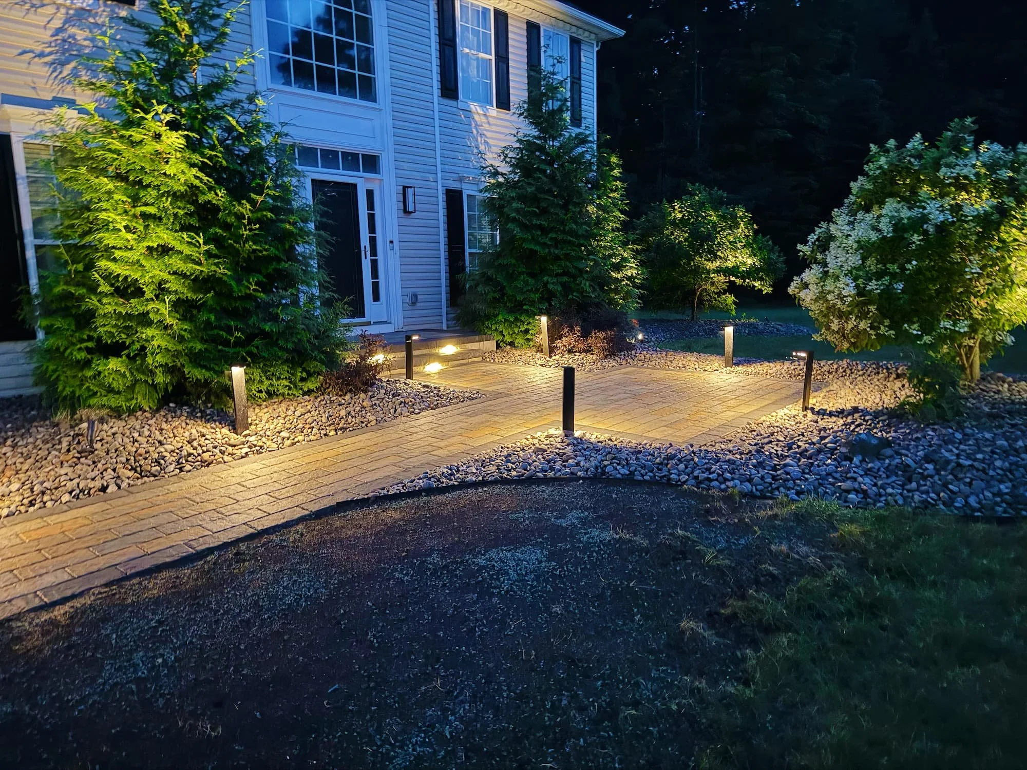 Custom paver entryway framed by decorative stone and landscaping at a Central NY residence.