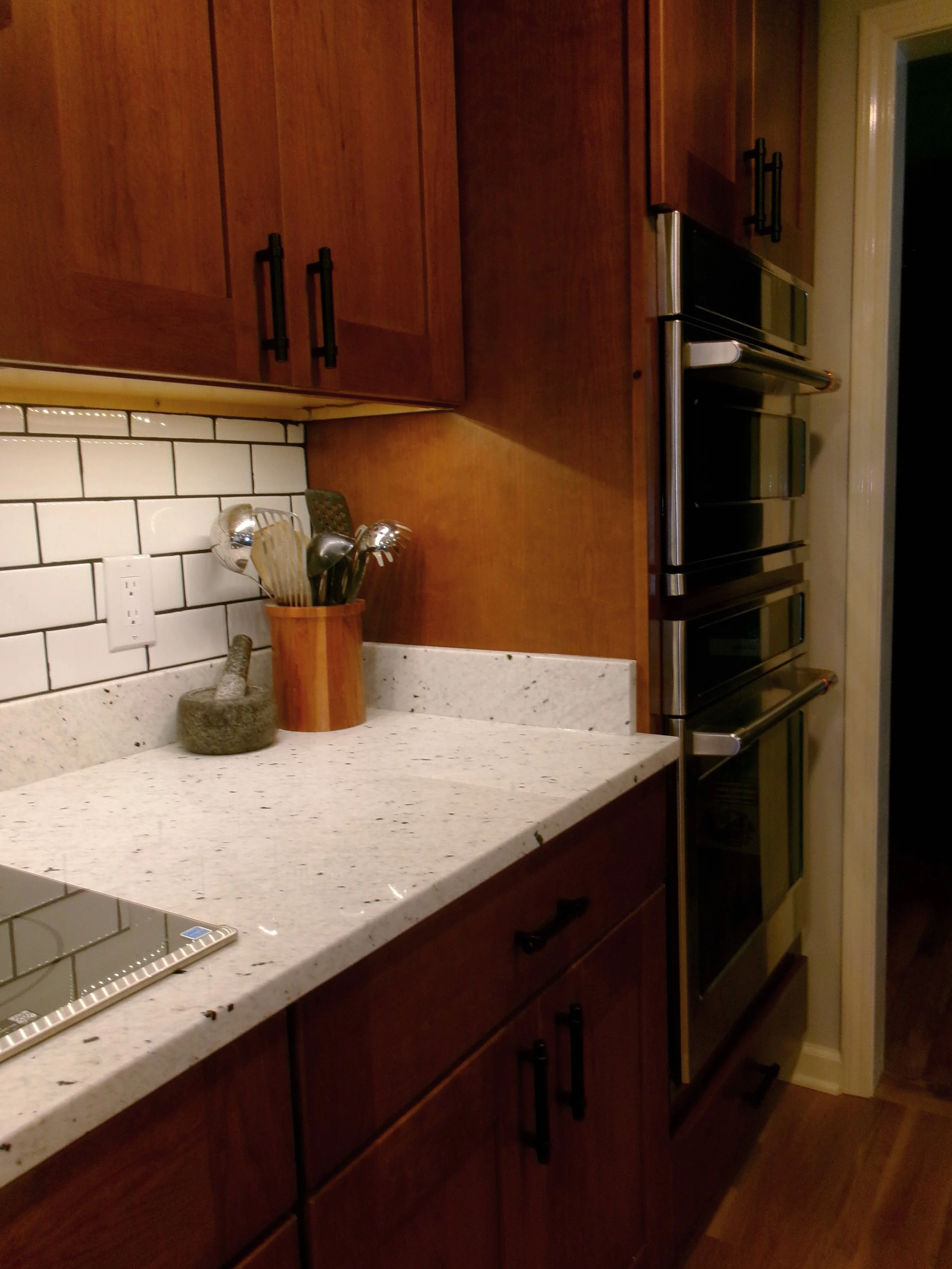 Kitchen renovation featuring wood cabinetry, light countertops, and subway tile backsplash in Central New York