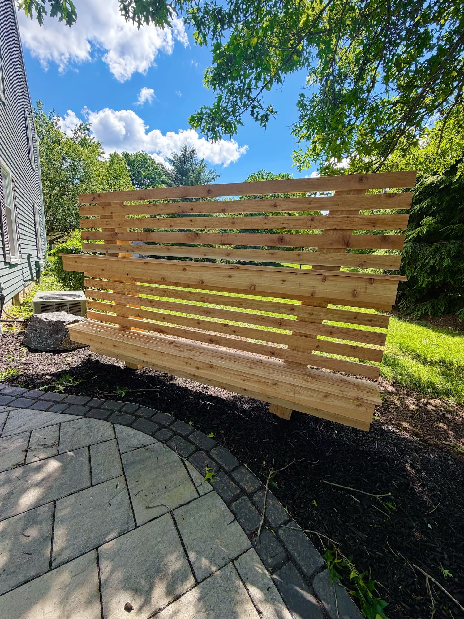 Custom paver patio with a modern wooden privacy screen in Central New York.