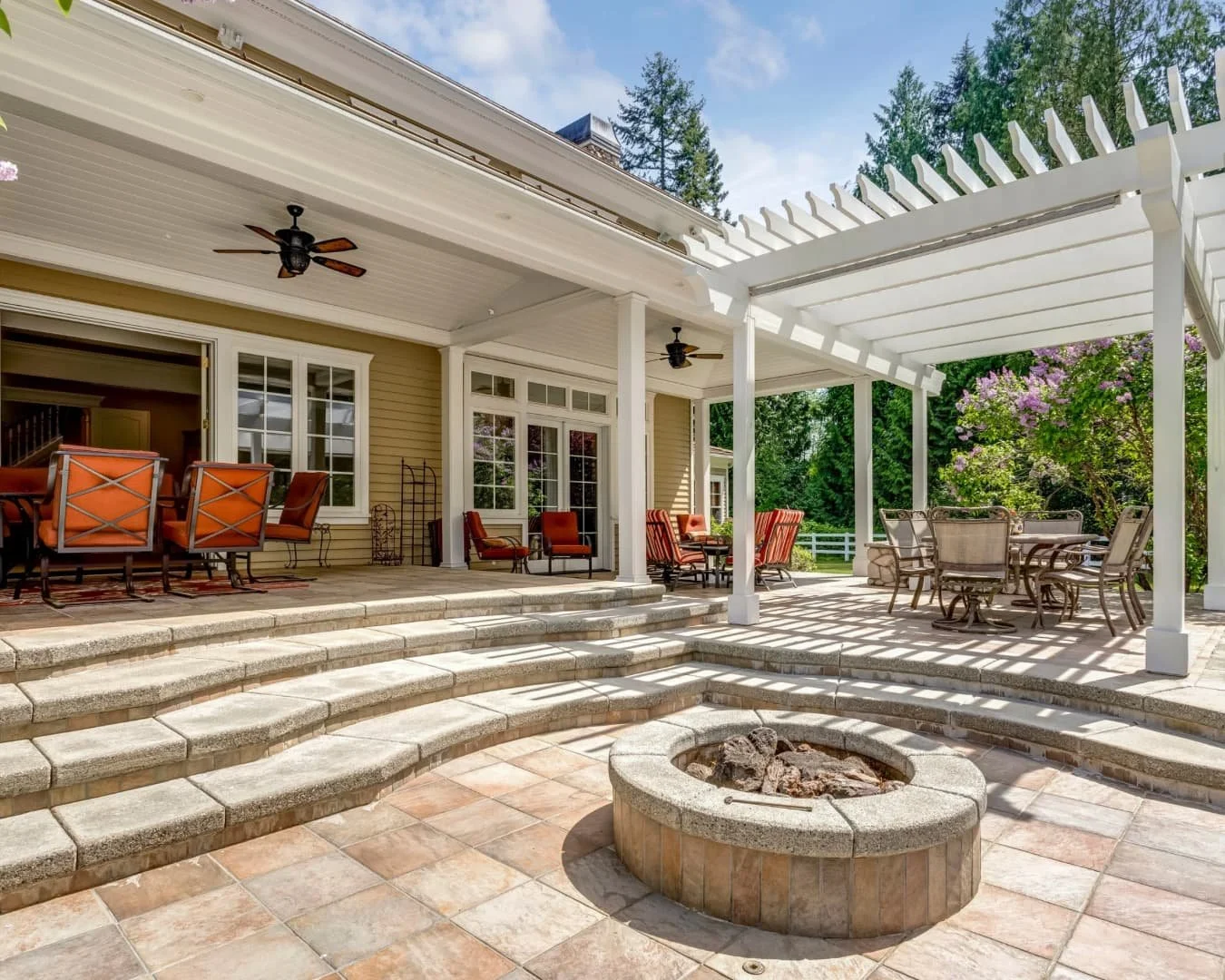 Patio inspiration with tiered steps, a fire feature, and a covered outdoor living area designed for entertaining.