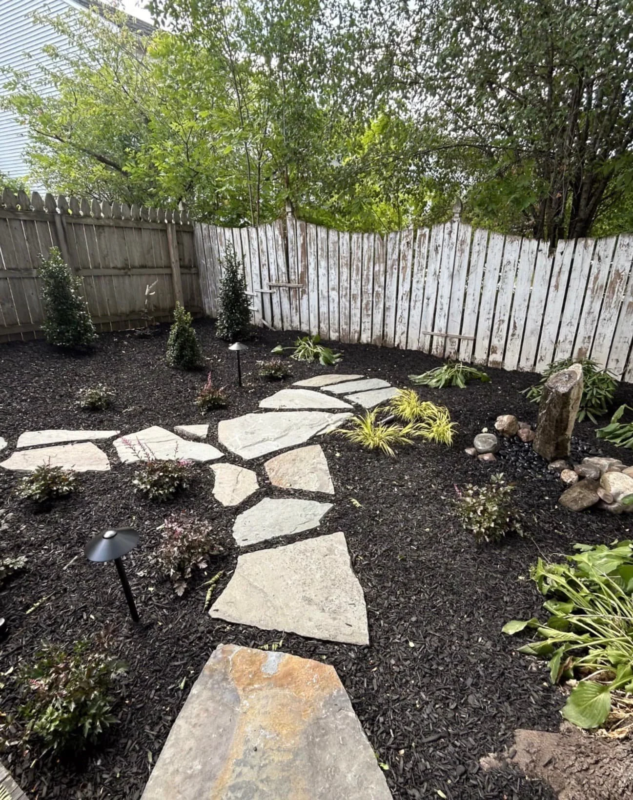 Tree bed and backyard landscaping at an Upstate New York home with fresh mulch, open lawn, and clean bed definition.