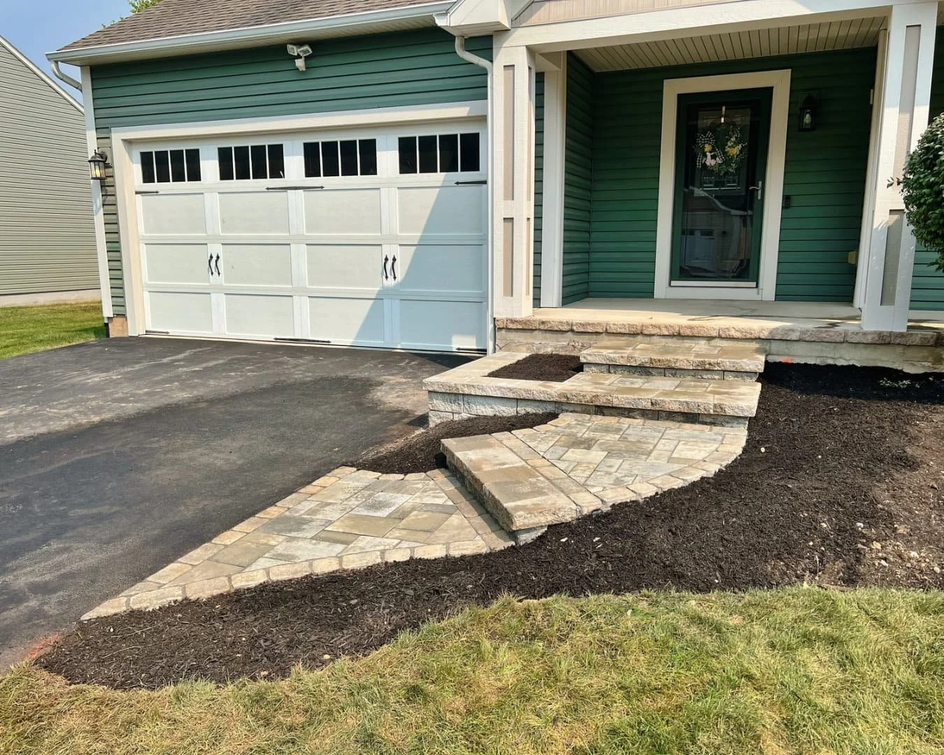 Curved front entry steps and planting bed completed by Pines and Pavers in Manlius, New York.