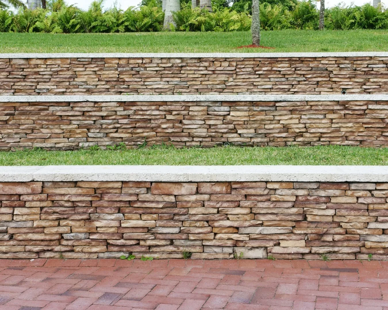 Curved retaining wall inspiration with a smooth stone cap, planting bed, and adjacent walkway.