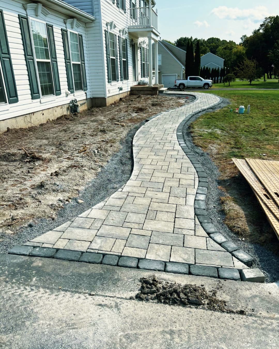 Curved front paver walkway at a Central New York home with dark border accents and a smooth flowing layout.