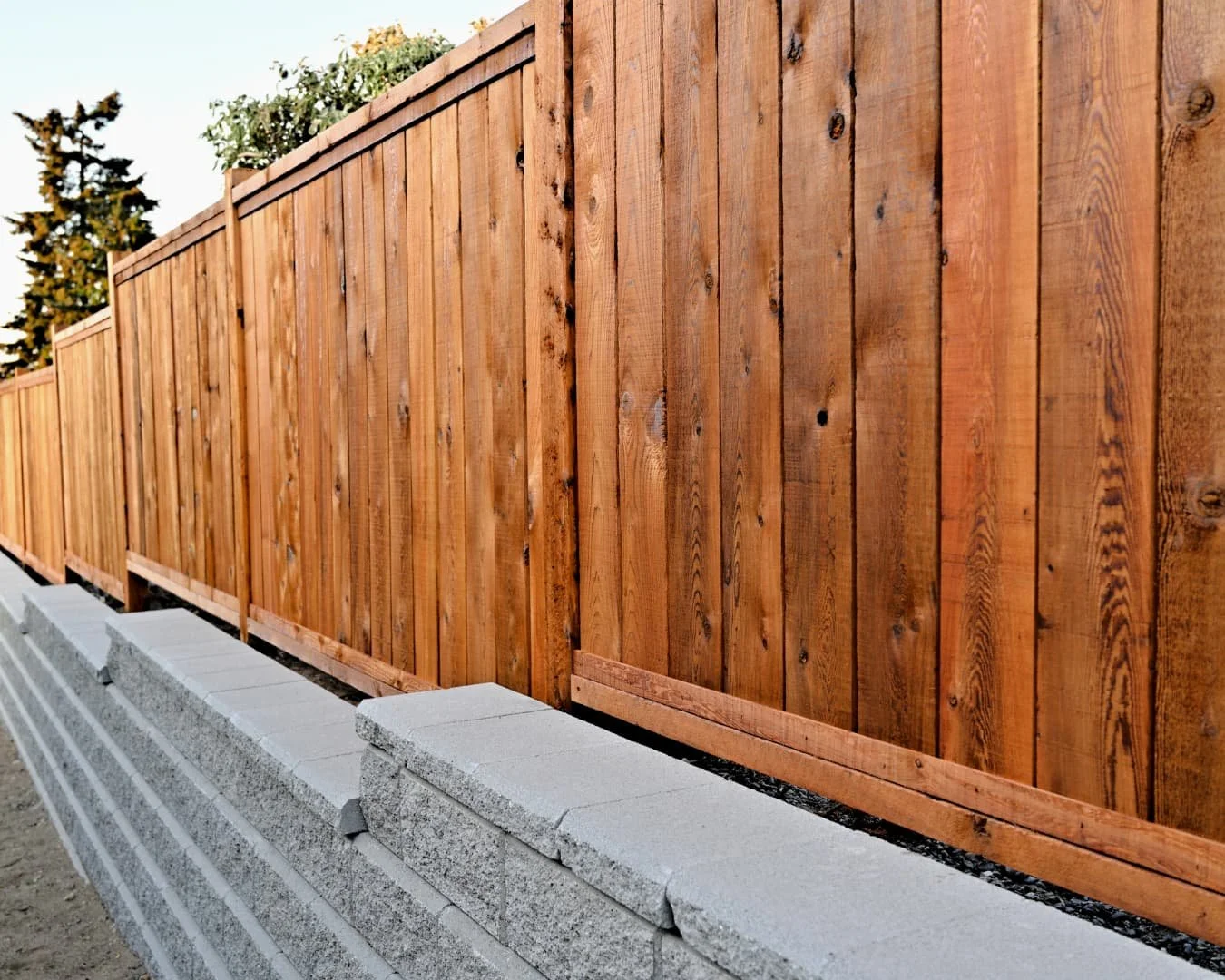 Retaining wall inspiration with a straight stone base wall paired with a wood privacy fence.