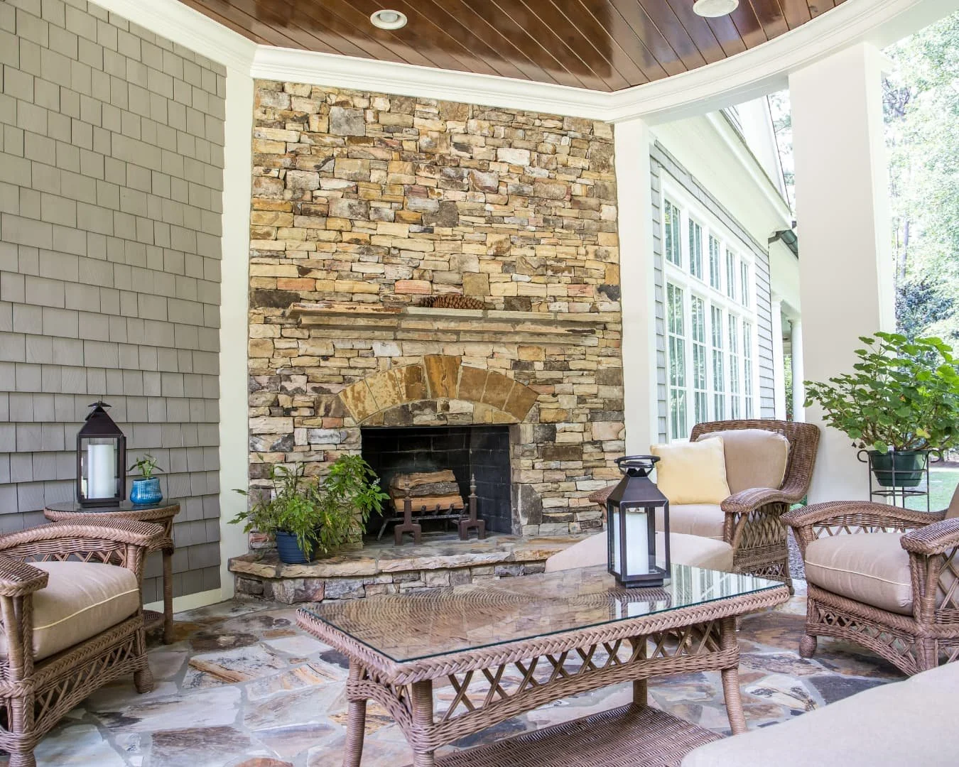 Outdoor fireplace inspiration featuring a stone fireplace built into a covered porch setting.