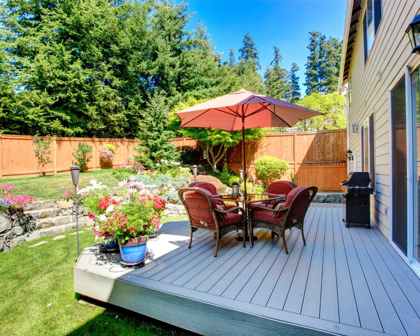 Deck inspiration with backyard seating area, umbrella, and privacy fencing beside the home.