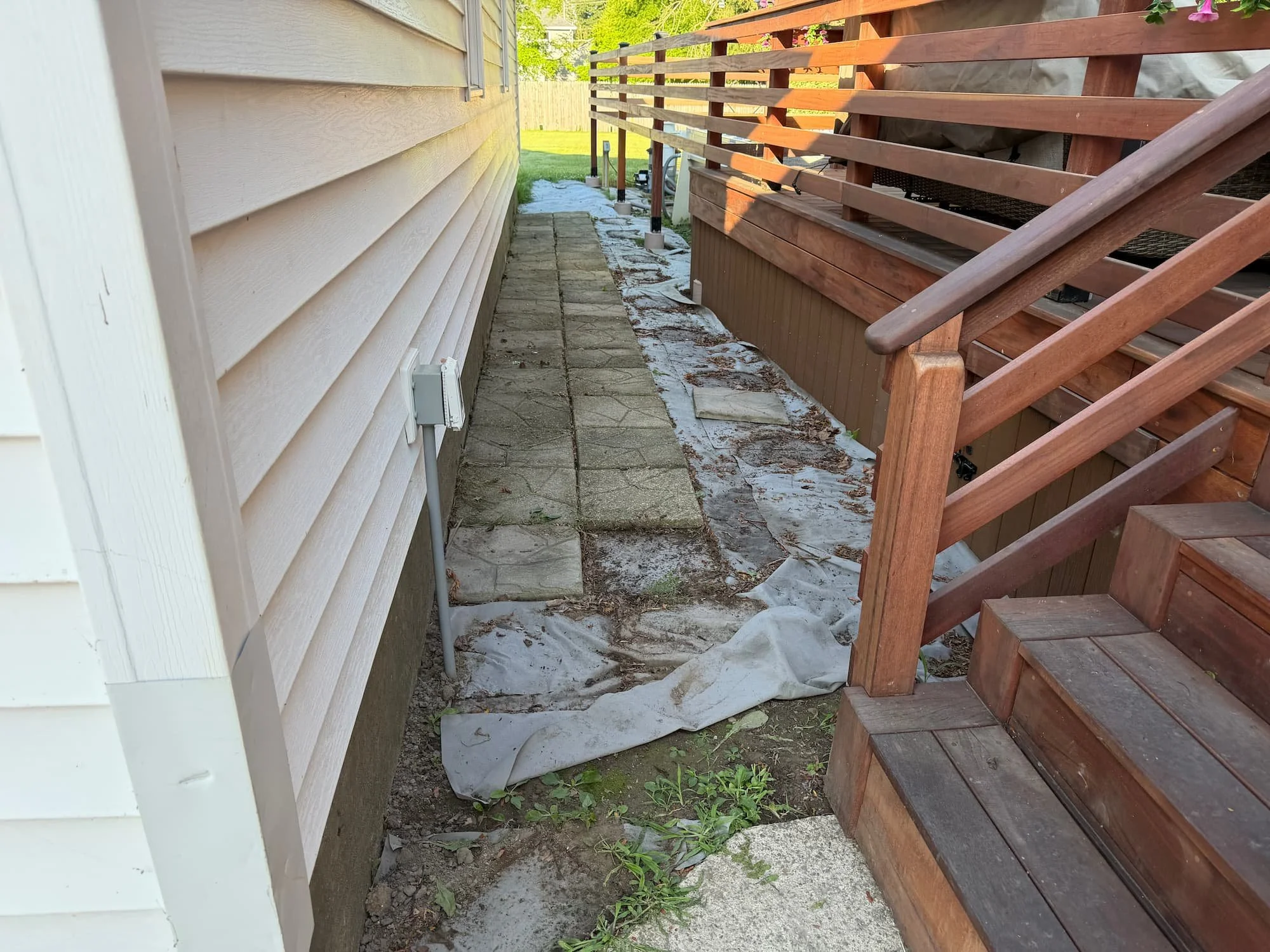 Newly installed paver walkway running alongside a residential deck in Central New York.